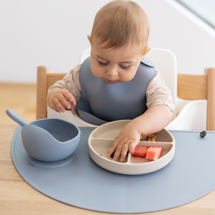Baby eating watermelon with mess-free silicone placemat and divided plate, easy clean food catcher for mealtime