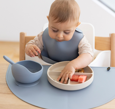 Baby eating watermelon with mess-free silicone placemat and divided plate, easy clean food catcher for mealtime