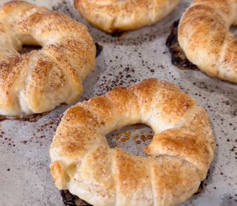 Freshly baked cinnamon sugar bagels on parchment paper, golden brown and flaky