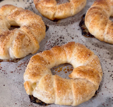 Freshly baked cinnamon sugar bagels on parchment paper, golden brown and flaky