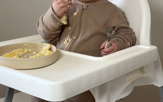 Baby eating messy meal in high chair with Catchy floor mat protecting flooring from food spills