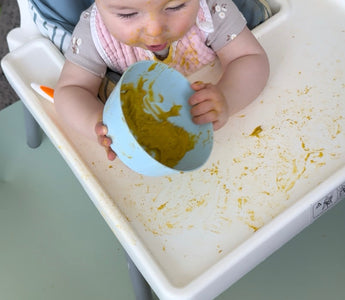Baby eating messy puree in high chair with food-safe catch mat, easy wipe clean, protects floors