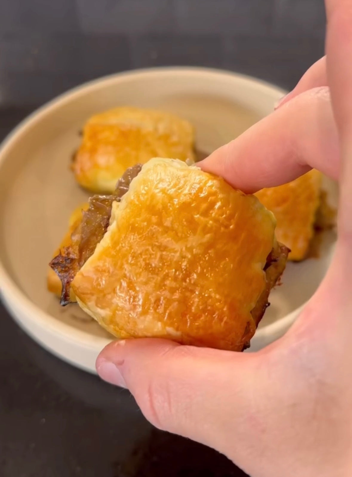 Hand holding golden-brown pastry with flaky crust, perfect for mess-free meals