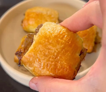Hand holding golden-brown pastry with flaky crust, perfect for mess-free meals
