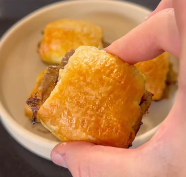 Hand holding golden-brown pastry with flaky crust, perfect for mess-free meals