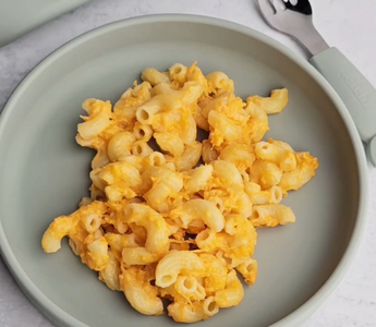 Mac and cheese on a sage green silicone plate with matching fork, mess-free meal solution