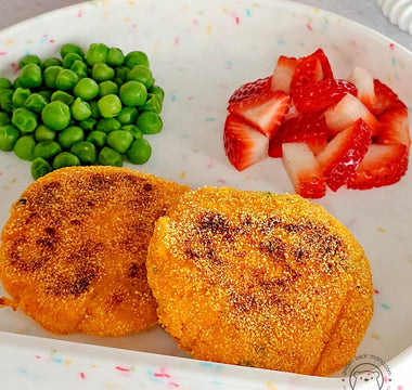 Kid-friendly meal with crispy patties, peas, and strawberries on colorful plate